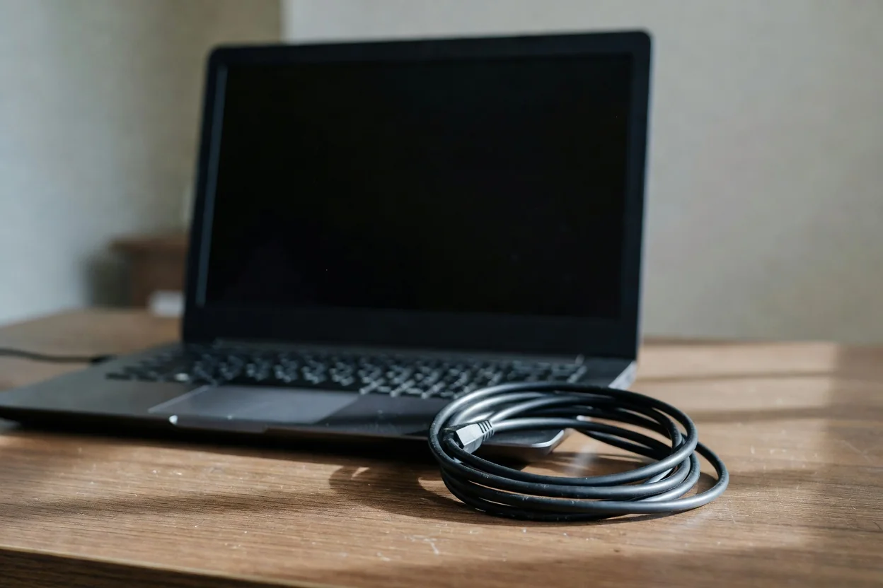 A laptop with a dark screen beside a coiled ethernet cable